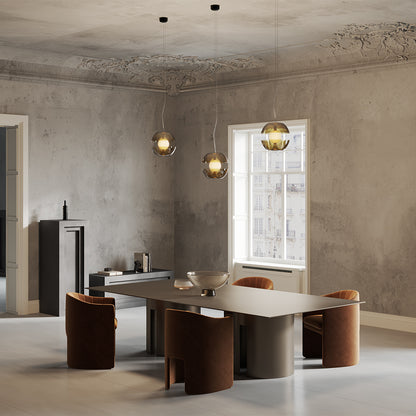 Modern dining room with a large metallic table and chairs, featuring a concrete wall and window.