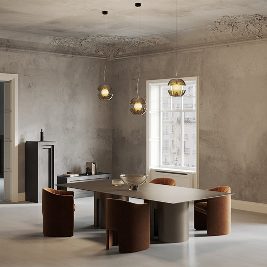Modern dining room with a large metallic table and chairs, featuring a concrete wall and window.