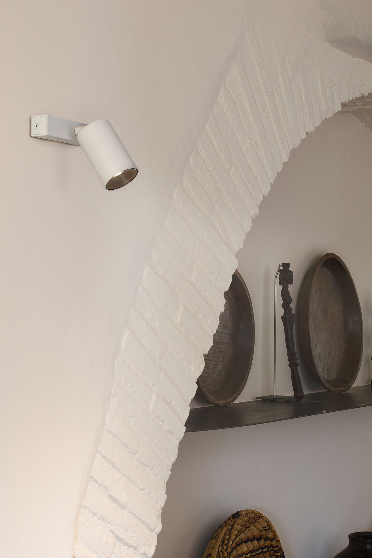 Wall-mounted light fixture on a white brick wall with decorative elements.