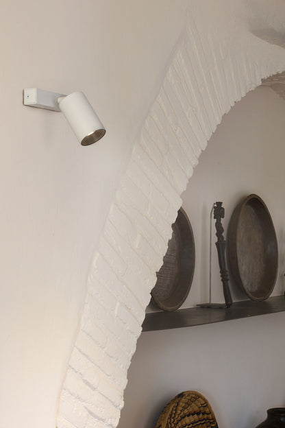 Wall-mounted light fixture on a white brick wall with decorative elements.