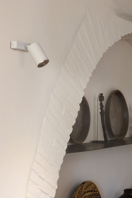 Wall-mounted light fixture on a white brick wall with decorative elements.