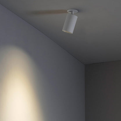 Ceiling light fixture casting a shadow on a wall in a minimalistic room.