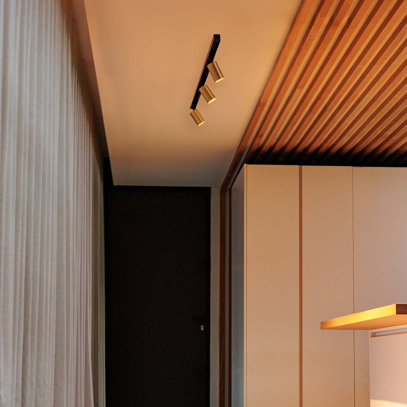 Modern interior with wooden ceiling, light fixture, and white curtains.