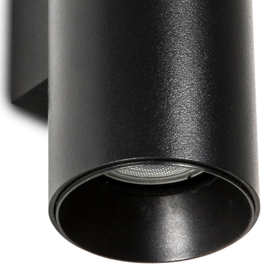 Close-up of a matte black cylindrical wall-mounted light fixture showing the open shade and internal reflector, set against a plain white background.