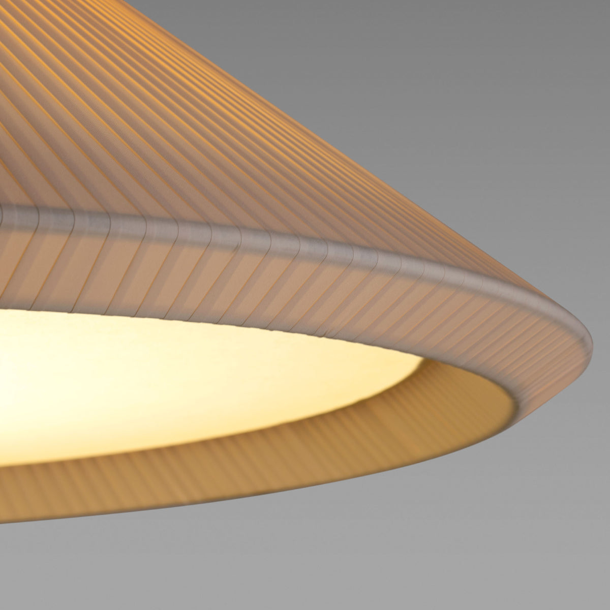 Close-up of a textured lampshade with a soft glow on a gray background