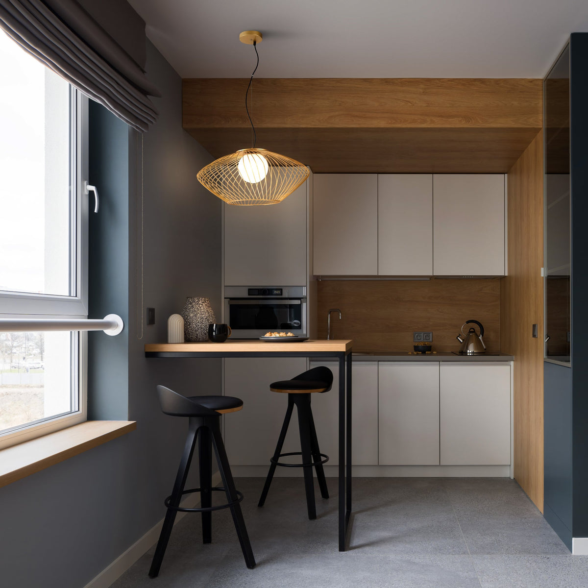 Modern kitchen with ceiling lamp gray walls, wooden countertops, and black bar stools.