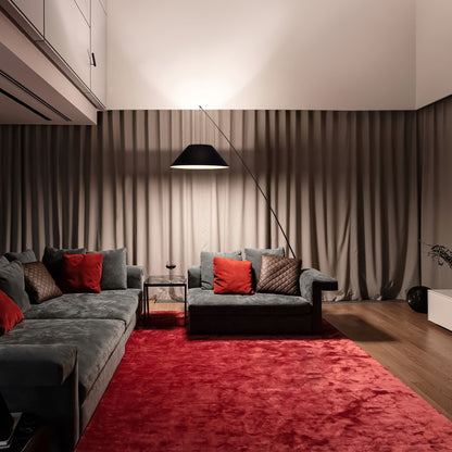 Modern living room with gray sofa, red pillows, and floor lamp.