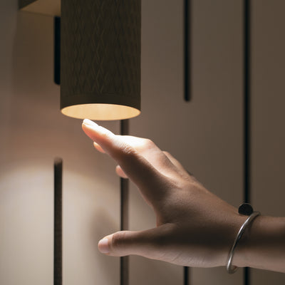 Hand touching a modern ceiling light fixture