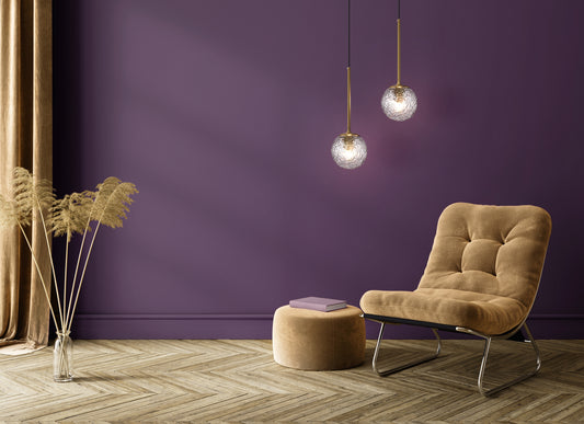 Modern living room with a brown armchair, ottoman, and lighting  against a purple wall.