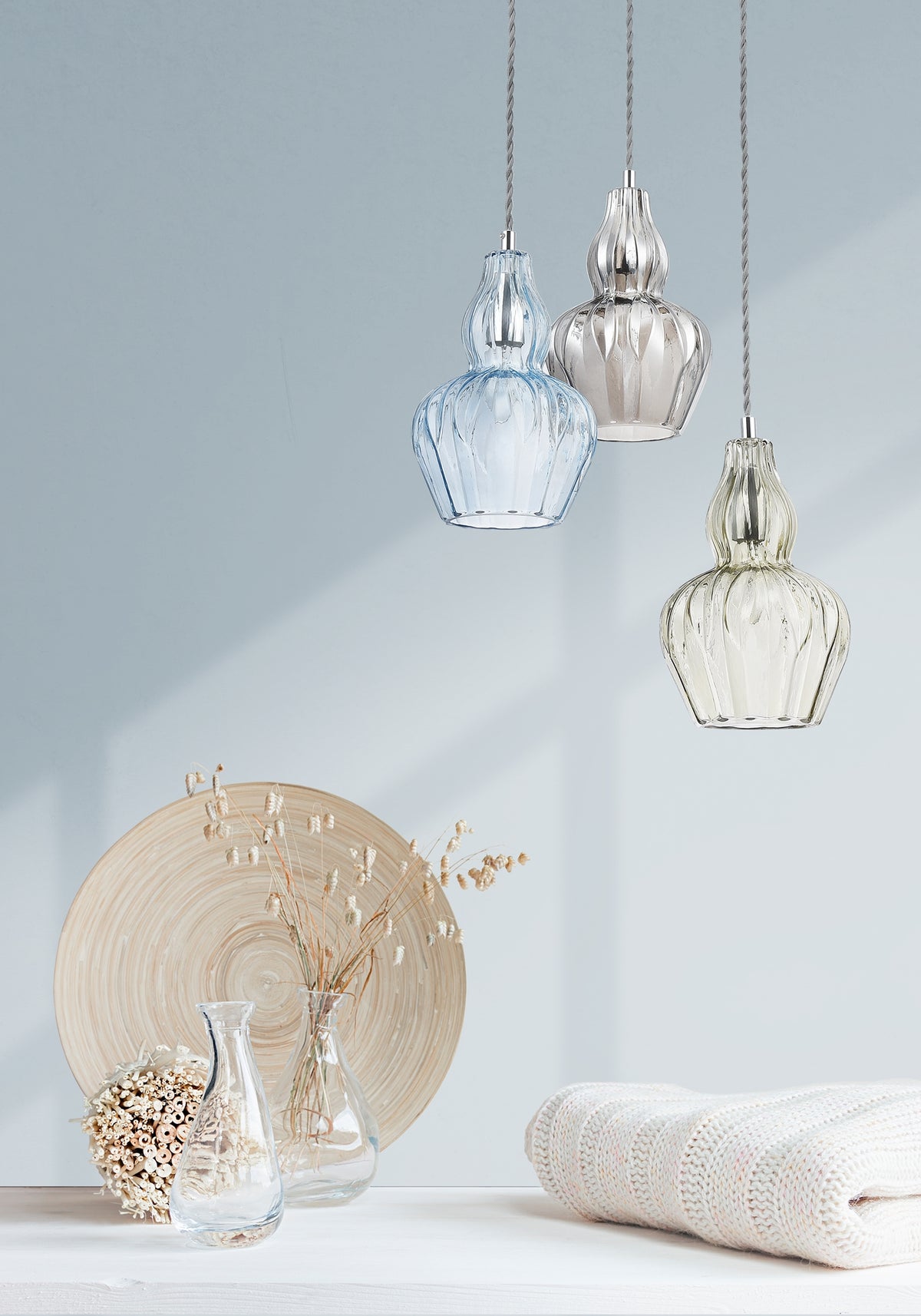 Three hanging glass lamps on a light gray background