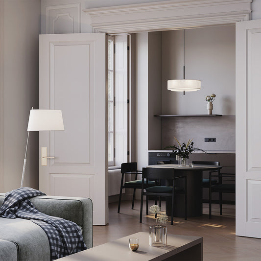 Modern living room with gray sofa, coffee table, and ceiling lamp and open door leading to kitchen.