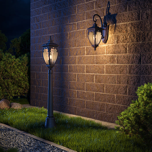 Outdoor lighting fixtures on a brick wall with grass and plants around.