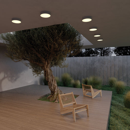 Outdoor patio area with wooden chairs and a tree under artificial lighting