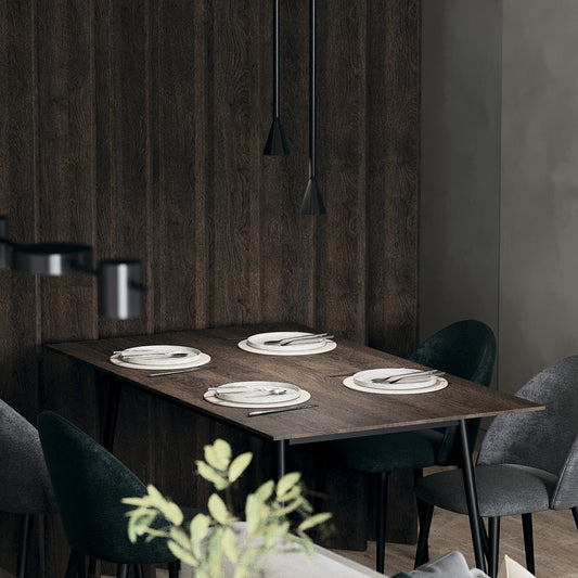 Dining table set with plates and lamp cutlery against a wooden wall.
