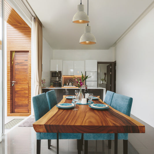 Modern kitchen with wooden dining table and pedant lighting, open door leading to outdoor area.