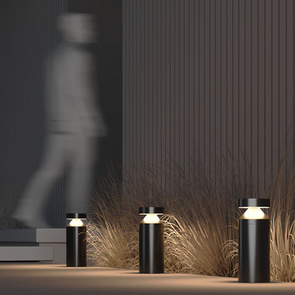 Modern outdoor lighting fixtures with grasses and a blurred figure in the background