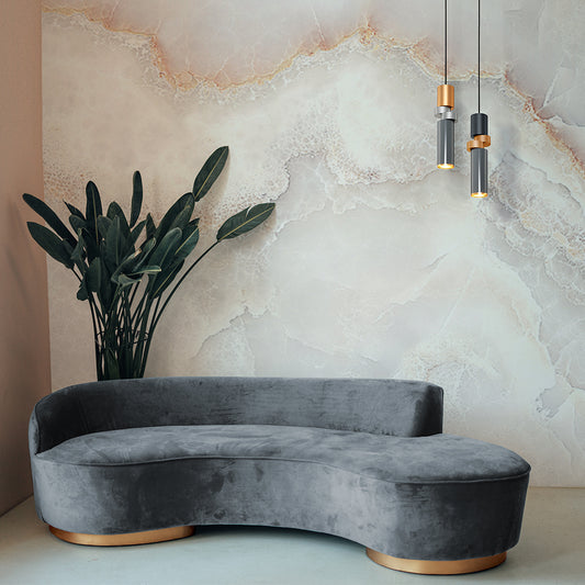 Gray velvet sofa in a room with a marble wall and pendant lamp