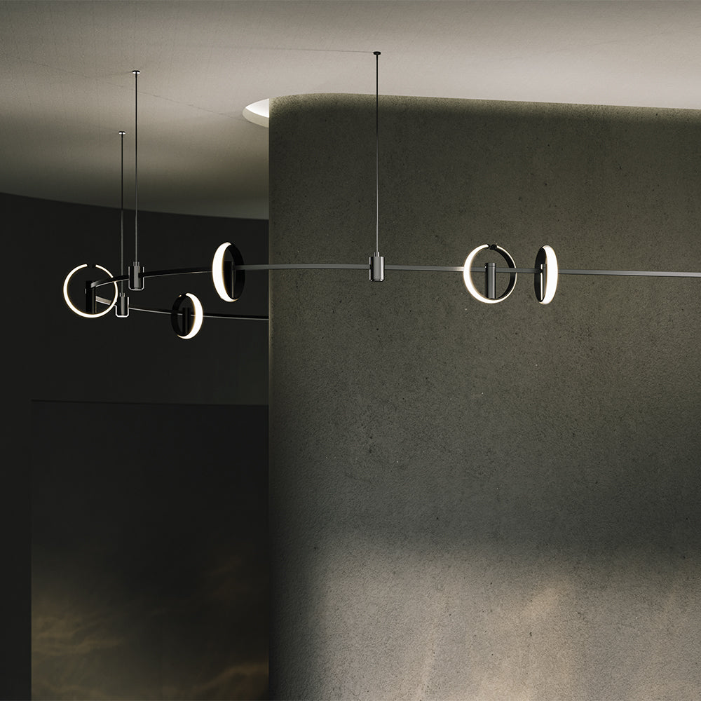 Modern chandelier with circular design hanging against a dark wall.
