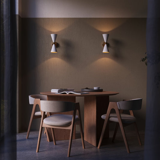 Dining area with wooden table and chairs under wall lights in a dimly lit room.