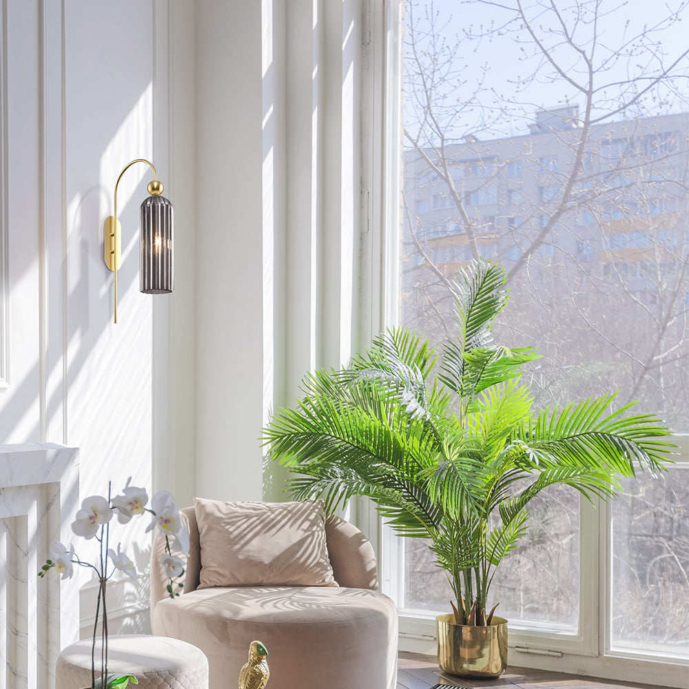 Modern living room with a beige armchair, decorative plant, and wall sconce.