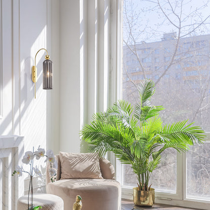 Modern living room with a beige armchair, decorative plant, and wall sconce.